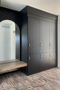 an empty room with black cabinets and wood flooring in the center, along with a wooden bench