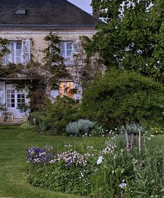 a large house with lots of flowers in the front yard