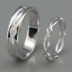 two wedding rings with an intricate design on the inside and outside, set against a gray background