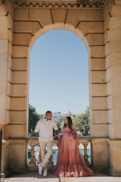 a man and woman standing in front of an arch