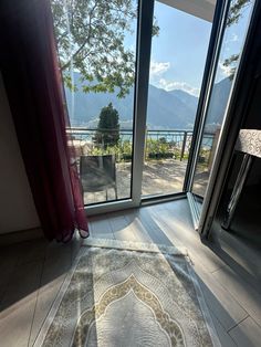 a living room with large windows and a rug on the floor