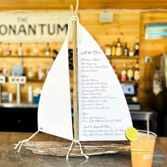 a table with a drink and a paper sailboat on top of it next to a bar