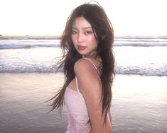 a beautiful young woman standing on top of a beach