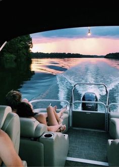 two people are sitting on the back of a boat in the water at sunset or dawn