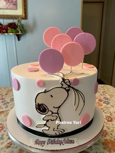 a birthday cake decorated with pink and white balloons