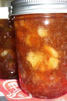 two jars filled with food sitting on top of a red and white table cloth next to each other