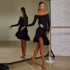 a woman is standing in front of a mirror wearing a black dress and high heels