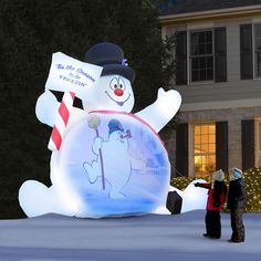 two people standing in front of a lighted snowman