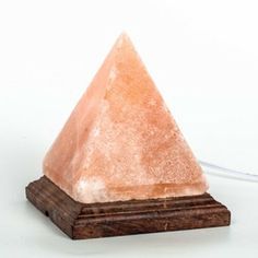 a small pink crystal pyramid sitting on top of a wooden stand