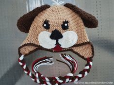 a knitted hat with a dog's face on it and a candy cane in the mouth