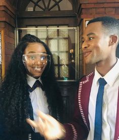 a man and woman wearing glasses standing next to each other in front of a door