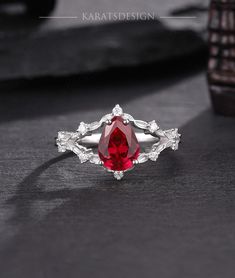 a ring with a red stone surrounded by white diamonds