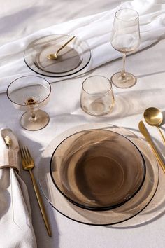 a table set with plates, silverware and gold colored utensils on it