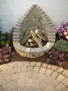 an outdoor fire pit surrounded by flowers and rocks