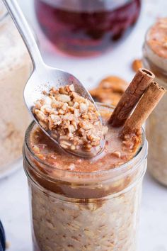 a spoon full of oatmeal with cinnamon sticks sticking out of the jar