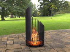 a fire pit sitting on top of a brick patio next to a lush green field