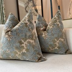 three pillows sitting on top of a couch in front of a mirror and framed pictures