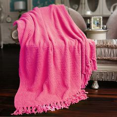 a bright pink blanket draped over a chair in a living room with white furniture and mirrors