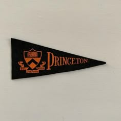 an orange and black pennant hanging on the side of a white wall that says princeton