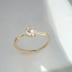 a yellow gold engagement ring with an oval cut diamond in the center and two small round diamonds on each side