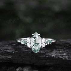 a green and white stone ring sitting on top of a piece of wood in the woods