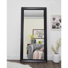 a black framed mirror sitting on top of a wooden floor next to a white rug