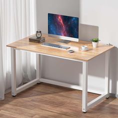 a desk with a computer on it in front of a white wall and wooden floor