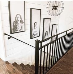 black and white photos hang on the wall next to an iron hand rail in front of a staircase