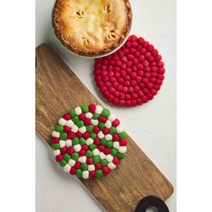 a wooden cutting board topped with two pies next to a cupcake covered in candy