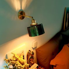 a lamp that is on the side of a wall next to a bed with pillows