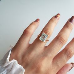 a woman's hand with a ring on it and an emerald stone in the middle