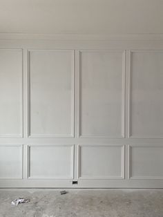 an empty room with white paneling on the walls