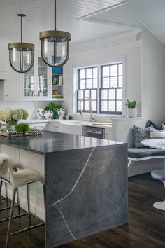 a large kitchen with an island in the middle and two stools at the end