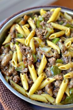 a bowl filled with pasta and meat on top of a table next to a napkin