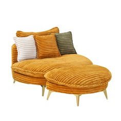 an orange couch with two pillows on top of it and a wooden footstool