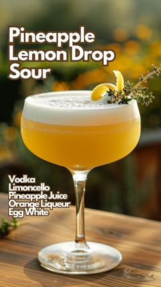 the pineapple lemon drop sour is served in a coupe glass with an orange garnish