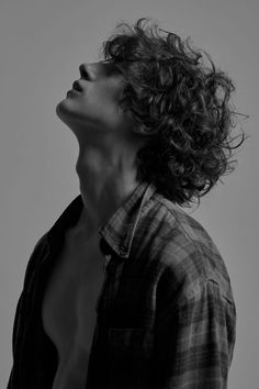 a shirtless man with curly hair looking up