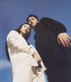 two people standing next to each other in front of a blue sky