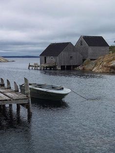 two small boats tied to the dock in front of some houses on an overcast day