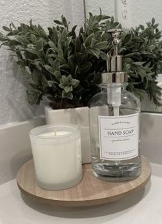 a bottle of hand soap sitting on top of a wooden tray next to a candle