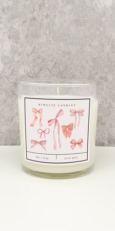 a candle with pink bows on it sitting on a white table next to a wall