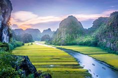 a river running through a lush green valley surrounded by tall rocks and grass covered mountains