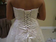 the back of a woman's wedding dress with laces and bows on it