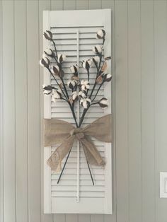 a white door with a bow and some flowers on the front window sill that is decorated with burlap