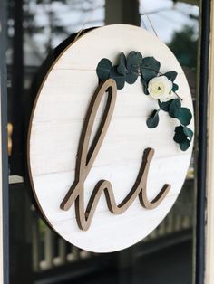 a wooden sign with the letter h on it and flowers hanging from it's side