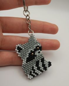 a hand holding a beaded keychain with a dog on it's face