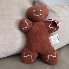 a brown teddy bear sitting on top of a couch next to a pillow with a tag