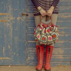 a woman wearing red boots holding a crocheted purse