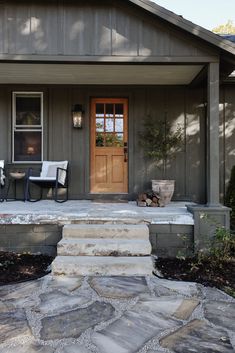 two chairs on the front porch of a house with stone steps leading up to it