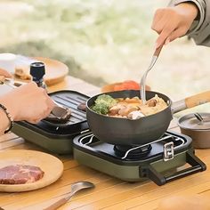 a person is cooking food on an outdoor stove